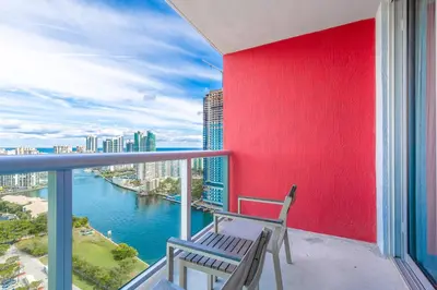 a chair on a balcony with a view of the water at Private Ocean Luxury Condos at Beachwalk Resort in Hallandale Beach
