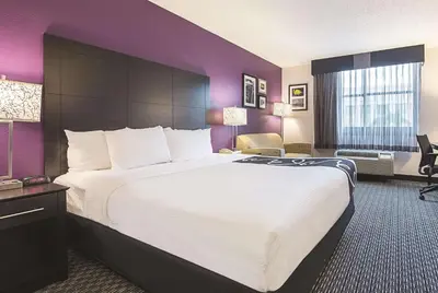 a hotel room with a large bed and purple walls at La Quinta by Wyndham Plantation at SW 6th St in Plantation