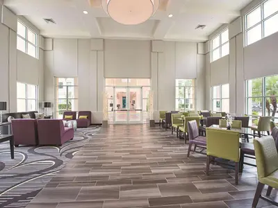 a dining room with tables and chairs and windows at La Quinta by Wyndham Plantation at SW 6th St in Plantation