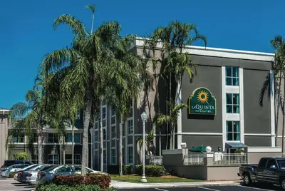 a hotel with palm trees in front of a building at La Quinta by Wyndham Plantation at SW 6th St in Plantation