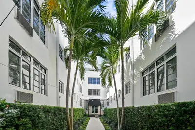 a row of palm trees in front of a building at Lincoln Arms Suites in Miami Beach