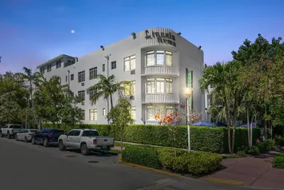 a white building with cars parked in front of it at Lincoln Arms Suites in Miami Beach
