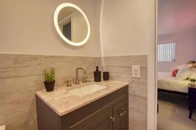 a bathroom with a sink and a mirror and a bed at 23 Palms Suites - Midtown Wynwood in Miami