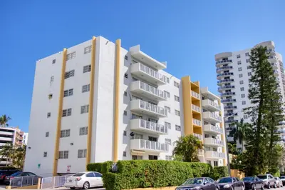 a white apartment building with cars parked in a parking lot at 23 Palms Suites - Midtown Wynwood in Miami
