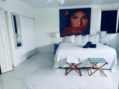 a bedroom with a large bed with a painting on the wall at Sunrise Penthouse ocean view terrace beach few steps away SOBE in Miami Beach