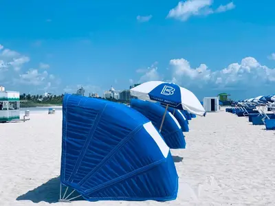 a row of blue beach chairs and umbrellas on a beach at Sunrise Penthouse ocean view terrace beach few steps away SOBE in Miami Beach