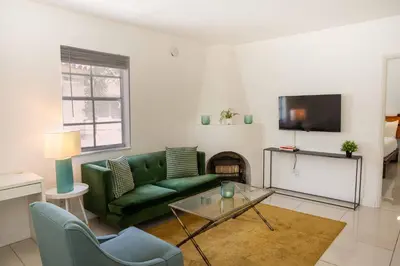 a living room with a green couch and a tv at Miami River Inn by Renzzi in Miami