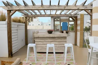 a patio with a wooden pergola and stools at The Local House in Miami Beach