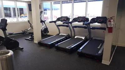 a row of treadmills in a gym with windows at Miami Direct Access to the beach in Miami Beach