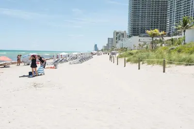 a woman standing on a beach with an umbrella at Hallandale Condo, Partial Ocean View Direct Beach and Pool Access Hollywood Beach in Hollywood
