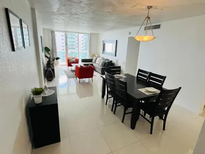 a dining room and living room with a table and chairs at Hallandale Beach Partial Ocean View Apartments in Hollywood