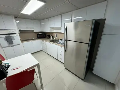 a kitchen with a stainless steel refrigerator and white cabinets at Hallandale Beach Partial Ocean View Apartments in Hollywood