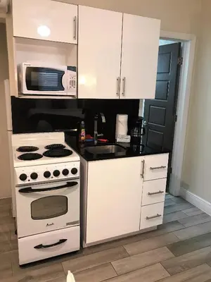 a white kitchen with a stove and a microwave at Caribbean Resort Suites in Hollywood