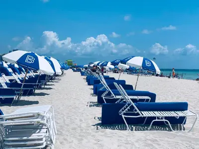 a row of blue and white chairs and umbrellas on a beach at Luxury white loft on Ocean Drive-South beach with a view in Miami Beach