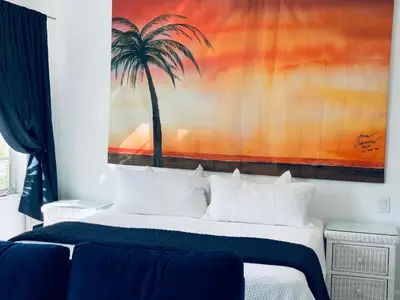 a bedroom with a palm tree painting on the wall at Luxury white loft on Ocean Drive-South beach with a view in Miami Beach