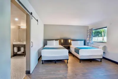 a hotel room with two beds and a bathroom at Motel 6-Fort Lauderdale, FL in Fort Lauderdale