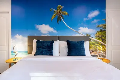 a bedroom with a bed with a palm tree mural at The Lauderdale Boutique Hotel in Fort Lauderdale
