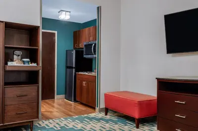 a small kitchen with a refrigerator and a red stool at Four Points by Sheraton Fort Lauderdale Airport - Dania Beach in Dania Beach