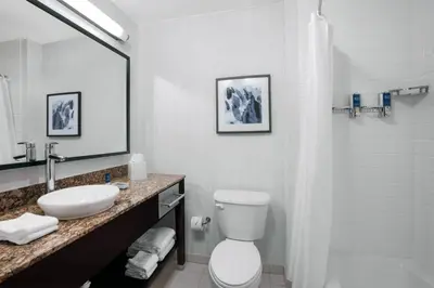 a bathroom with a sink and a toilet and a mirror at Four Points by Sheraton Fort Lauderdale Airport - Dania Beach in Dania Beach