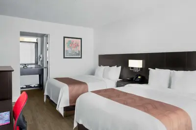 a hotel room with two beds and a red chair at Quality Inn Miami South in Kendall