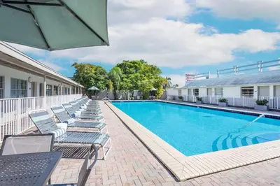 a swimming pool with lounge chairs and an umbrella at Days Inn by Wyndham Miami Airport North in Miami