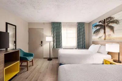 a hotel room with two beds and a television at Days Inn by Wyndham Miami Airport North in Miami