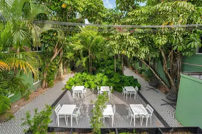 a patio with white tables and chairs in a garden at Atrium Hotel, Trademark Collection by Wyndham in Miami