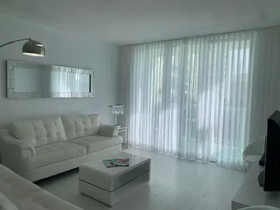 a living room with a white couch and a large window at Tides Apt on Hollywood Beach in Hollywood