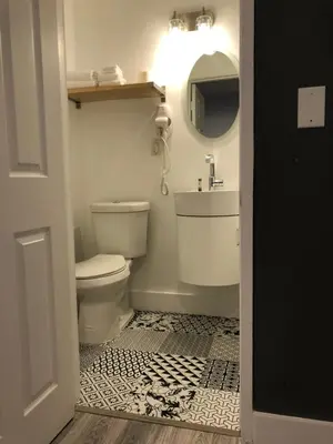 a bathroom with a toilet and a sink and a mirror at Oasis Hotel in Fort Lauderdale