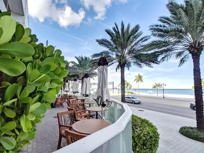a balcony with tables and umbrellas and the beach at WVR Vacation Residences 506 in Fort Lauderdale