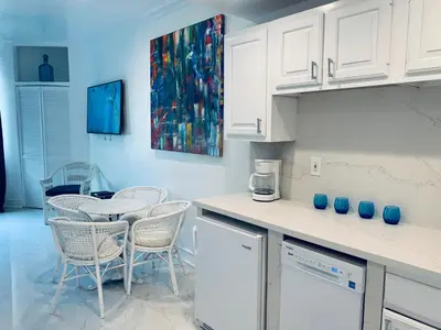 a kitchen with white cabinets and a table and chairs at SOBE OCEAN VIEW OCEAN DR charming studio -316 in Miami Beach