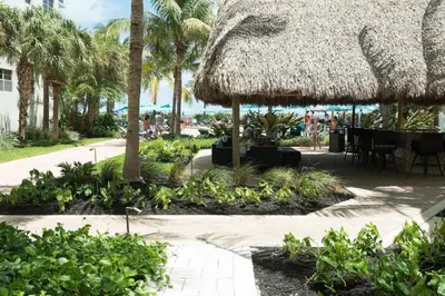 a patio with a straw umbrella and tables and palm trees at Miami Hollywood 2 Bedroom on the Beach 007-21mar in Hollywood