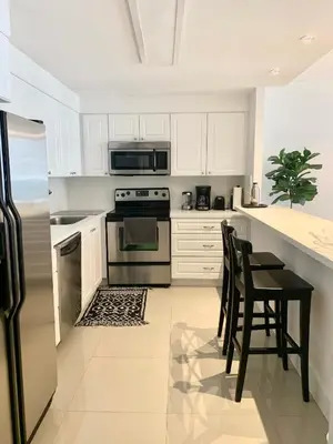 a kitchen with white cabinets and a table and chairs at Miami Sunny Isles ocean reserve 704 in Miami