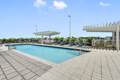 a large swimming pool with chairs and a umbrella at Miami Midtown Luxury Apartment in Miami