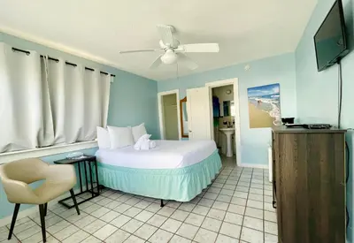 a bedroom with a bed and a chair and a television at St Maurice Beach Inn in Hollywood