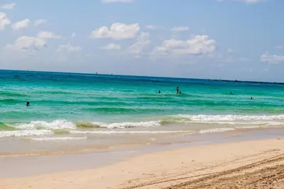 a group of people in the water at the beach at 2 Bedroom 2 Bath With Patio On 11th Collins ave in Miami Beach