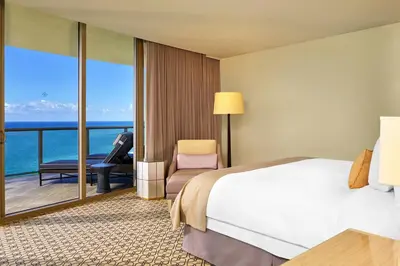 a bedroom with a bed and a balcony with the ocean at The St. Regis Bal Harbour Resort in Miami Beach