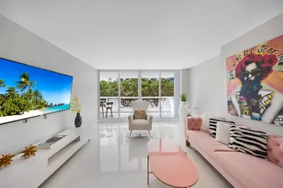 a living room with a pink couch and a flat screen tv at StayCozy Apartments at The Grand in Miami