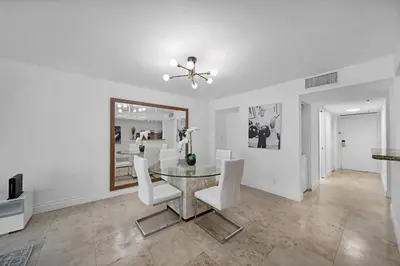a dining room with a glass table and white chairs at StayCozy Apartments at The Grand in Miami