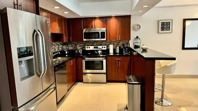 a kitchen with wooden cabinets and a stainless steel refrigerator at Sunny Isles Condo Resort in Miami Beach