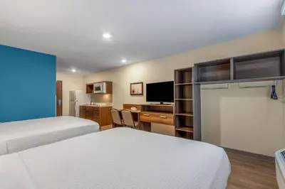 a hotel room with two beds and a desk at WoodSpring Suites Miramar in Miramar