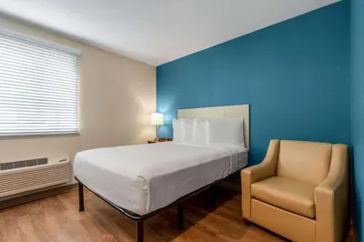 a bedroom with a bed and a chair in it at WoodSpring Suites Miramar in Miramar