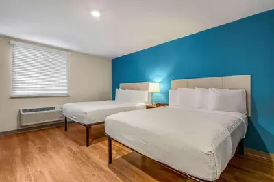 a bedroom with two beds and a blue wall at WoodSpring Suites Miramar in Miramar