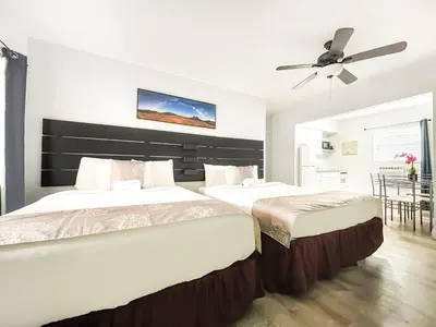 two beds in a bedroom with a ceiling fan at The Seagull in Hollywood