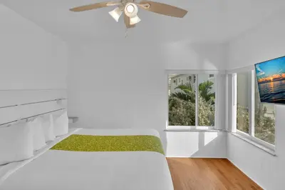 a white bedroom with a bed and a flat screen tv at The Seagull in Hollywood