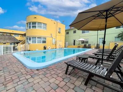 a swimming pool with a bench and an umbrella at Hollywood Beach Seaside in Hollywood