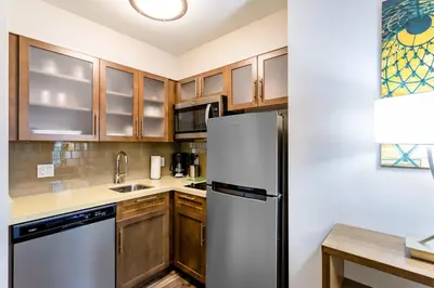 a kitchen with wooden cabinets and a refrigerator at Staybridge Suites - Fort Lauderdale Airport - West by IHG in Davie