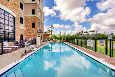 a pool at a hotel with chairs and a building at Staybridge Suites - Fort Lauderdale Airport - West by IHG in Davie