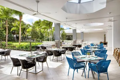 a restaurant with tables and chairs and palm trees at Le Meridien Dania Beach at Fort Lauderdale Airport in Dania Beach