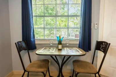 a table with two chairs and a window with blue curtains at The Blue Door Inn in Fort Lauderdale